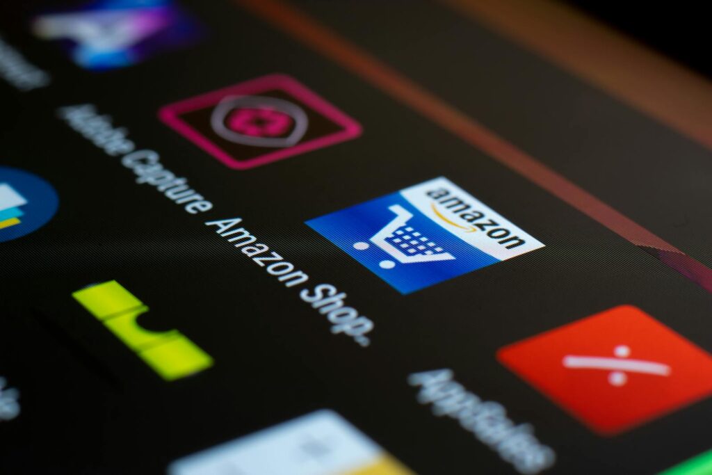Gros plan de l'icône de l'application Amazon sur un écran de smartphone. Idéal pour les achats en ligne et les thèmes technologiques.