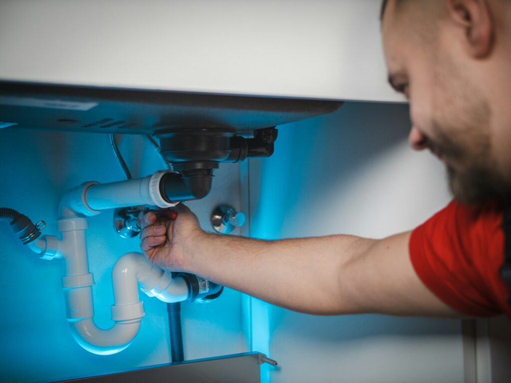 un homme travaillant sur un siphon dans un mur