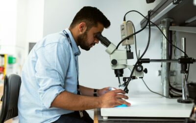 homme en chemise bleue utilisant un microscope noir et argent