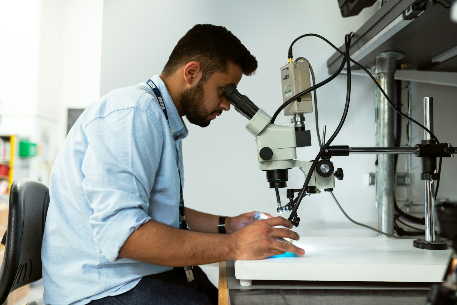 homme en chemise bleue utilisant un microscope noir et argent