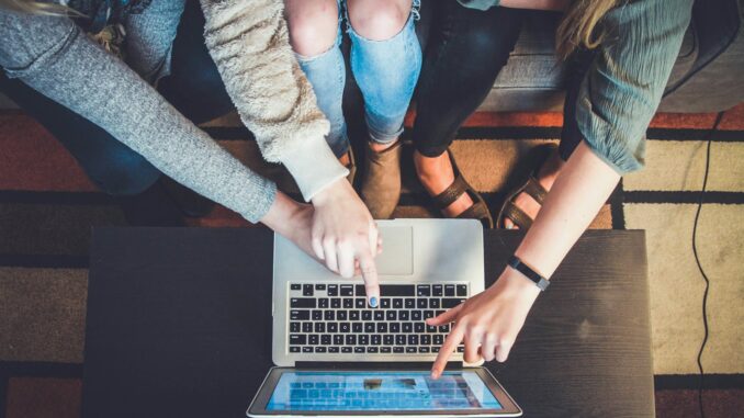 Échange des Connaissances : Un Pilier du Partage et de l’Apprentissage Collaboratif Trois personnes réunies autour d'un laptop pour échanger
