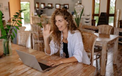 Influenceuse souriante ayant un appel vidéo dans un cadre à domicile avec un ordinateur portable.