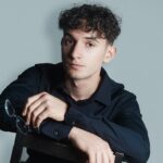 un jeune bloggeur passionné assis sur une chaise tenant une paire de lunettes