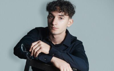 un jeune bloggeur passionné assis sur une chaise tenant une paire de lunettes